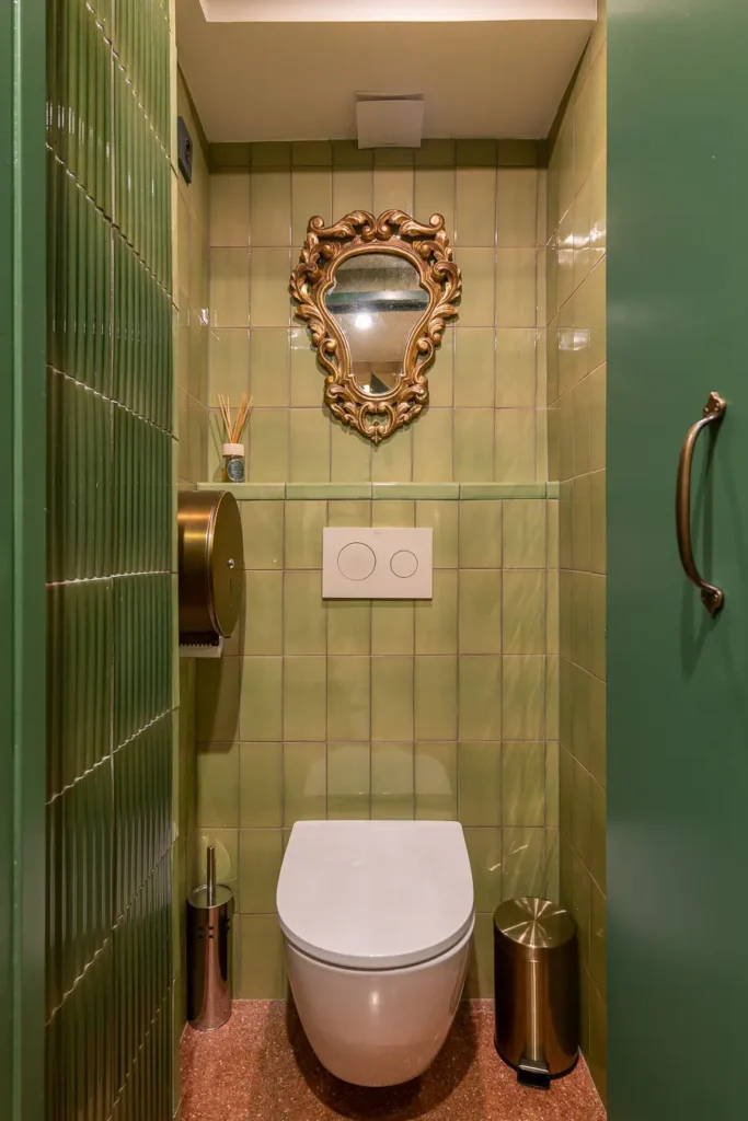 baño con azulejos verdes y espejo antiguo