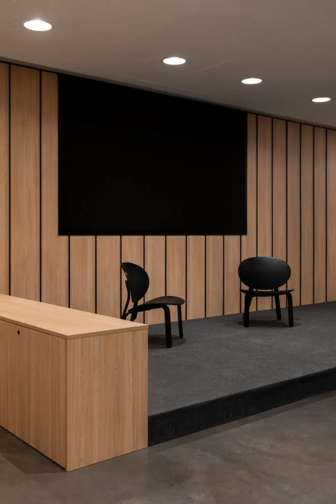 escenario con dos sillas negras frente a panel de madera