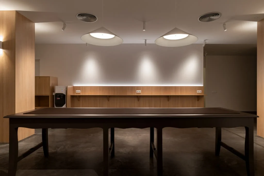 mesa de madera oscura centrada bajo lamparas colgantes blancas