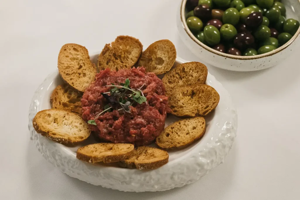 tartar de carne con tostadas y aceitunas verdes y negras