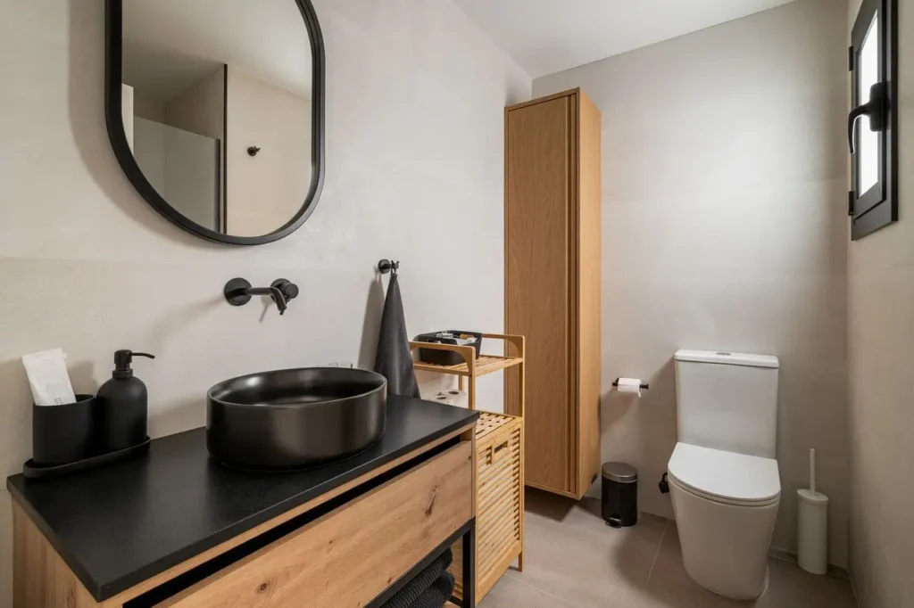 bano moderno con lavabo negro y muebles de madera