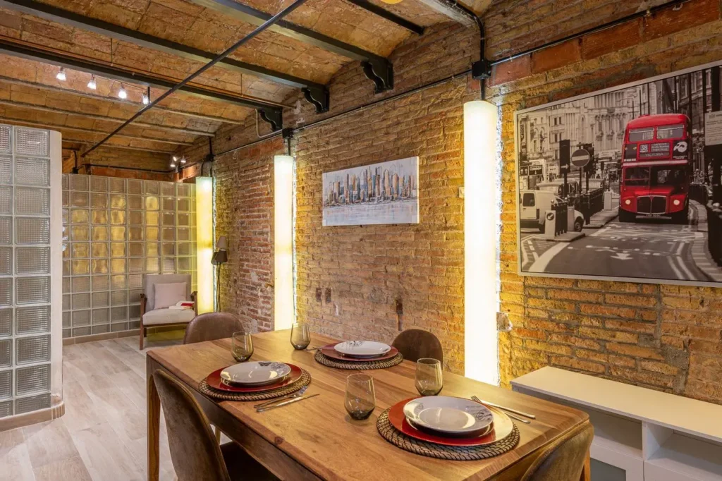comedor moderno estilo industrial con pared de ladrillo visto y mesa de madera iluminacion calida