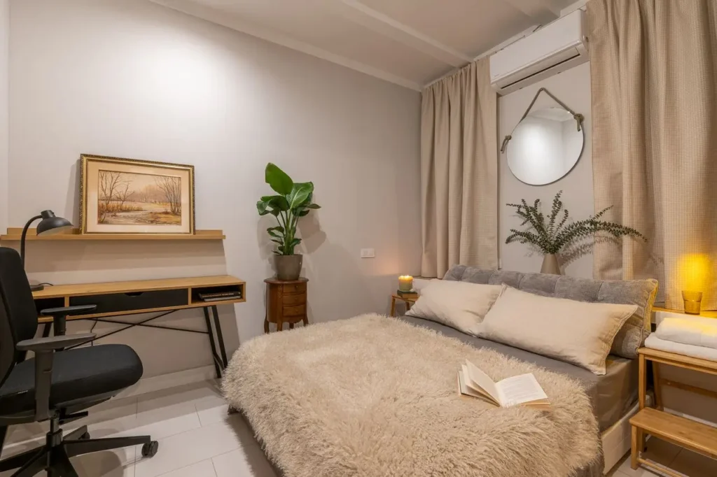 dormitorio calido con escritorio planta y cama con manta suave