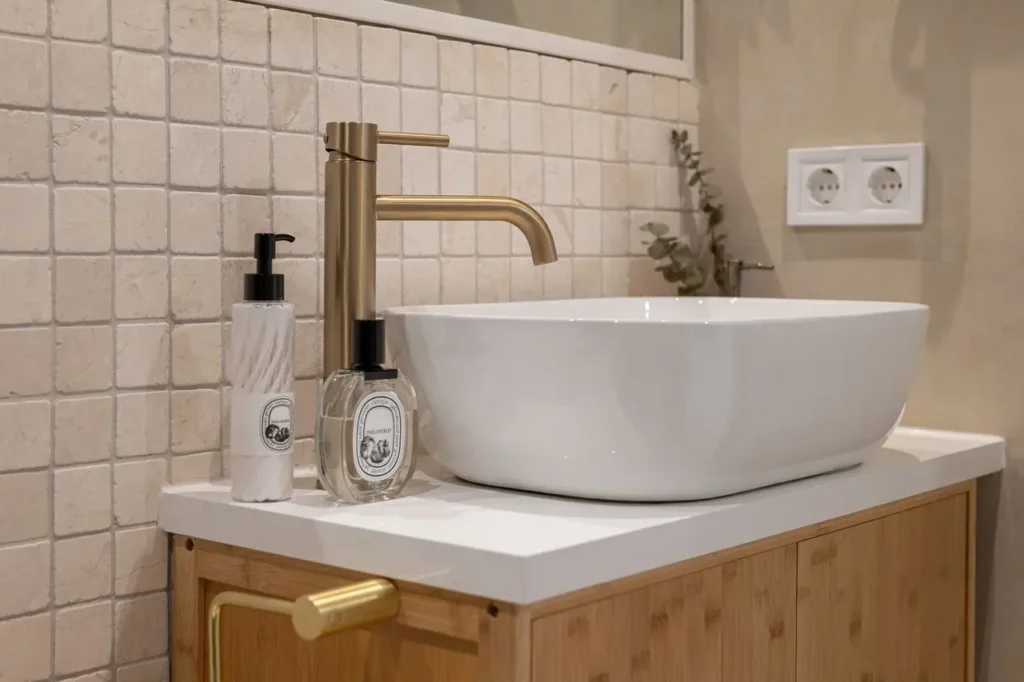 lavabo moderno con grifo dorado y azulejos texturizados