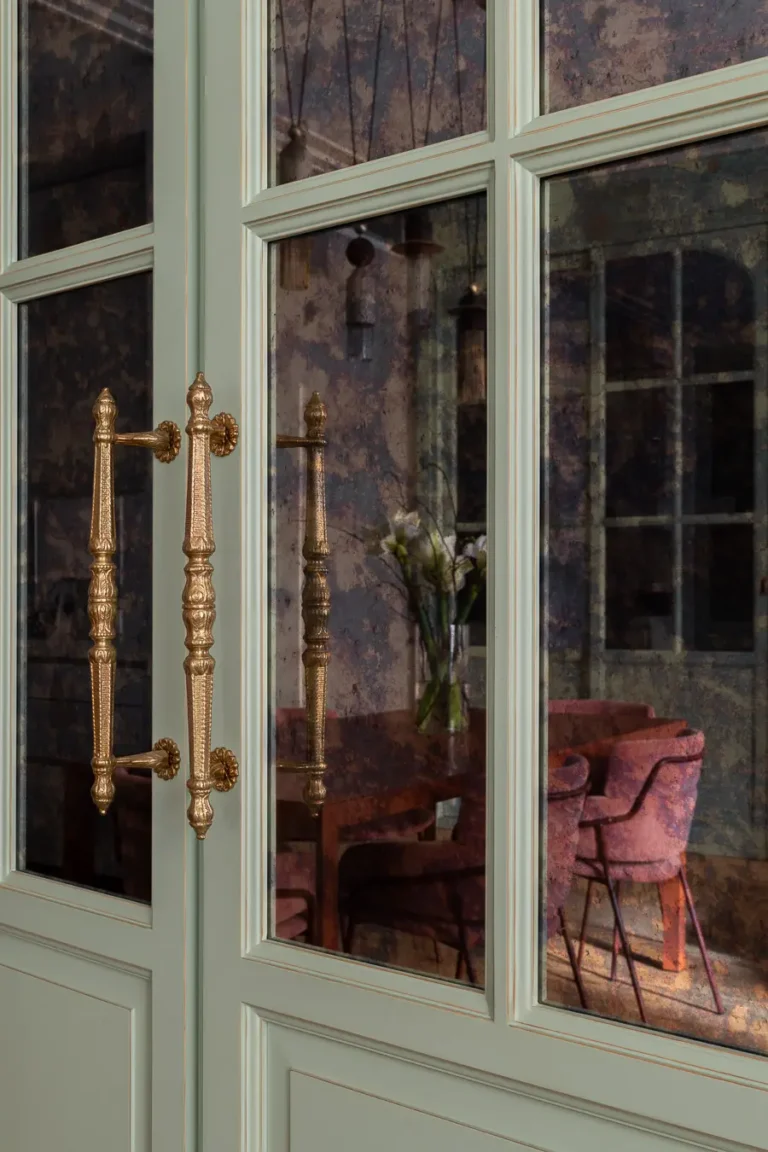detalle de puertas de vidrio con tiradores dorados y reflejo interior