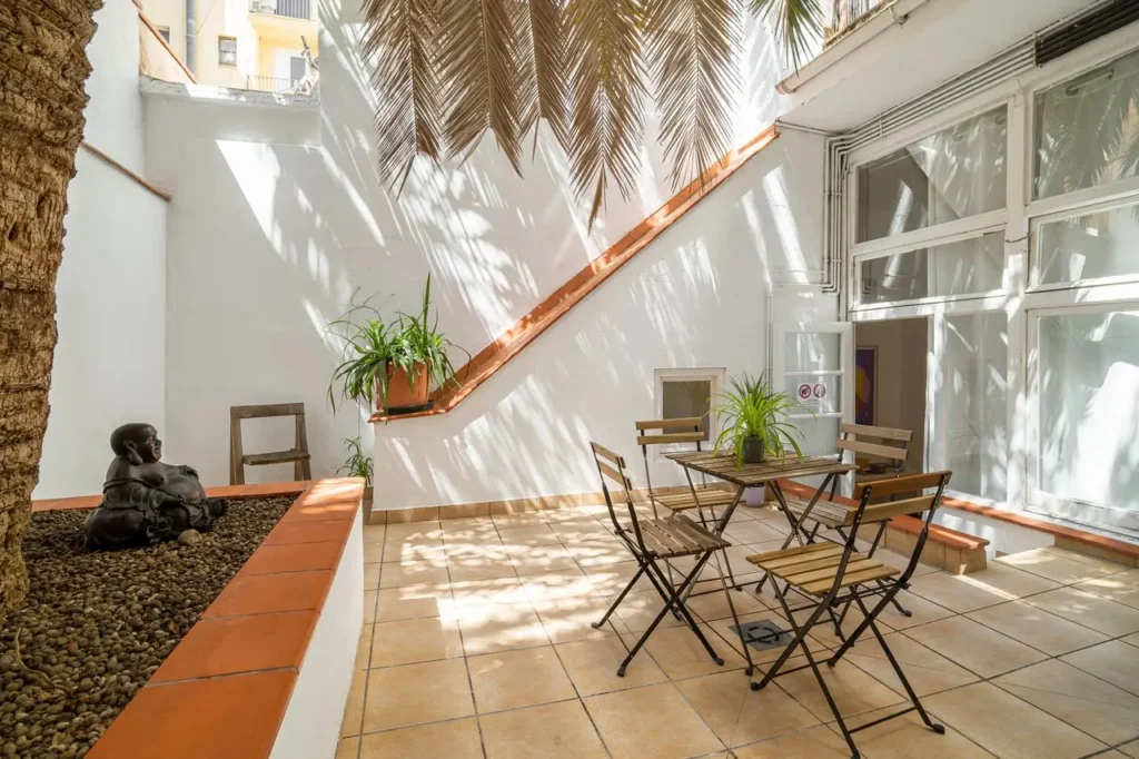 patio interior luminoso mesa sillas madera plantas sombra
