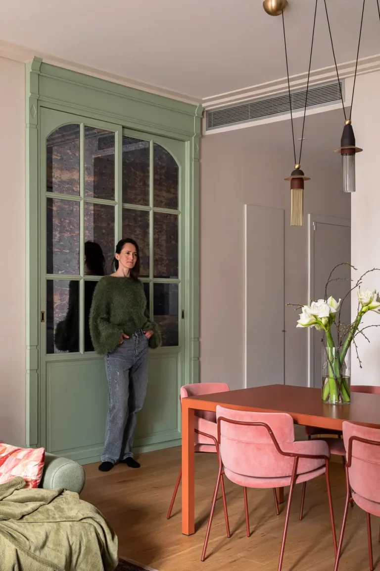 persona de pie en salón moderno junto a mueble verde y mesa de comedor