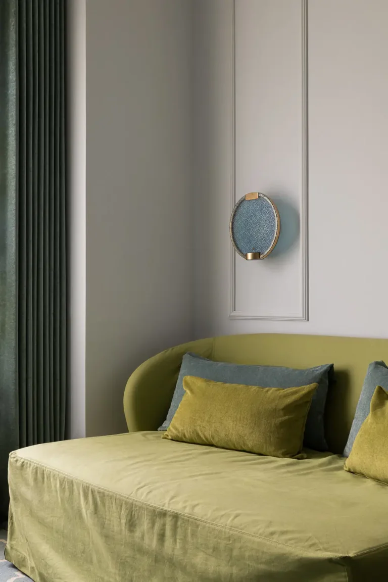 sofá verde con cojines y lámpara de pared decorativa