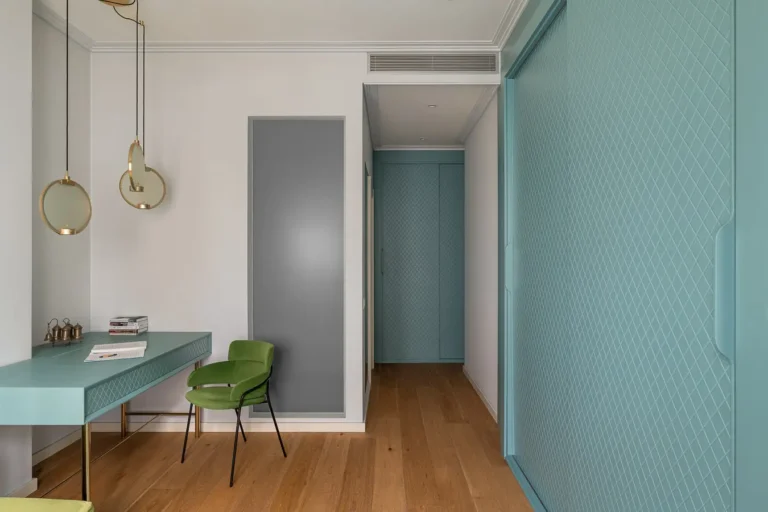 zona de trabajo moderna con escritorio turquesa y silla verde junto a pasillo