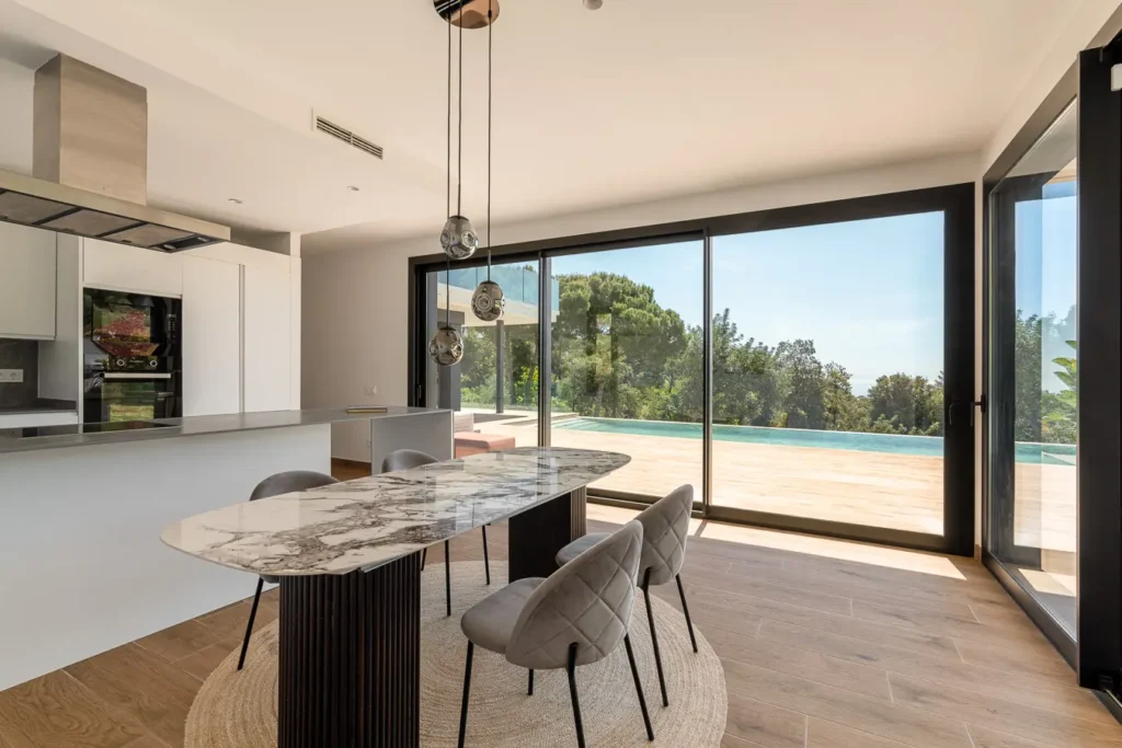 mesa de comedor junto a ventanales con vista al jardin