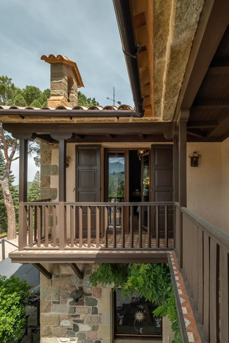 balcon de casa de piedra con barandilla de madera y contraventanas