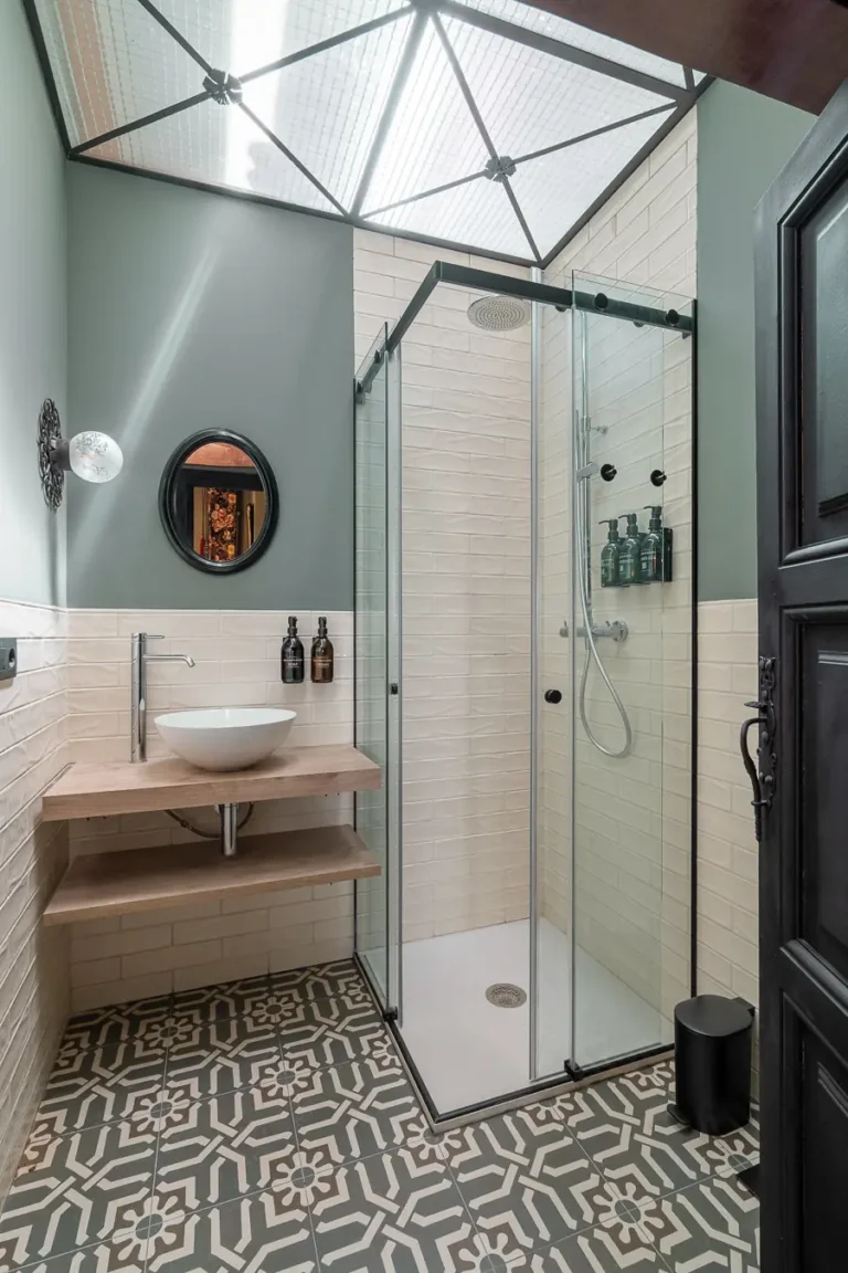 bano con ducha acristalada lavabo sobre encimera y suelo geometrico