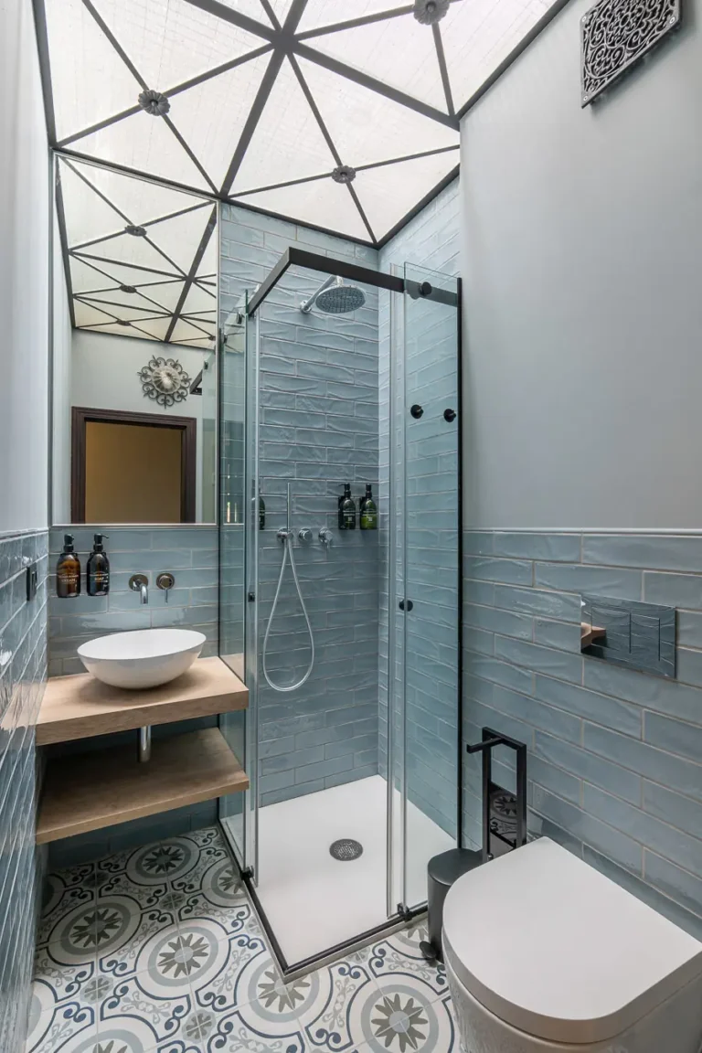 bano con ducha de cristal azulejos azules y suelo hidraulico