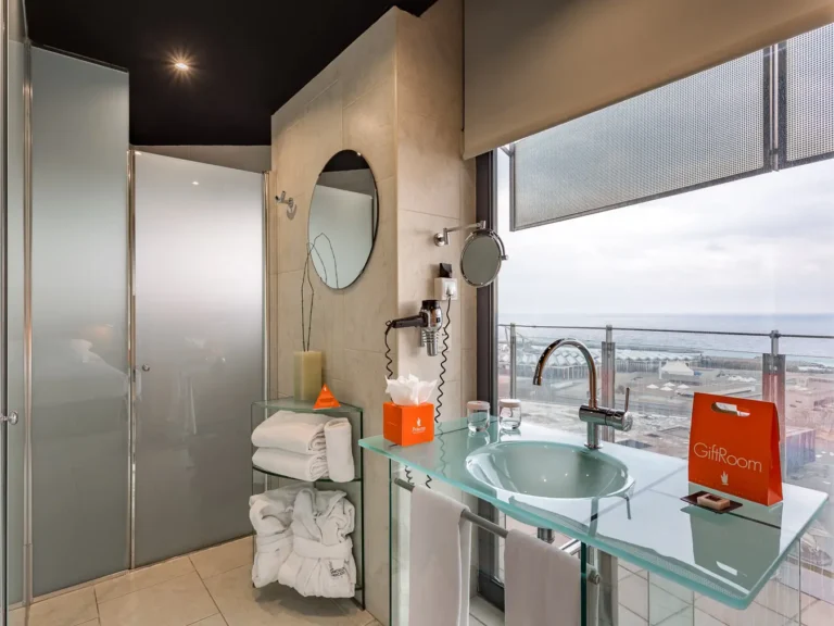 bano hotel con lavabo de cristal y vistas al mar