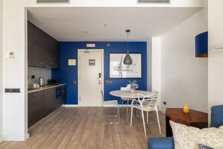 comedor de apartamento de hotel con cocina y pared azul