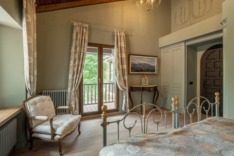 dormitorio clasico con sillon tapizado cortinas florales y balcon