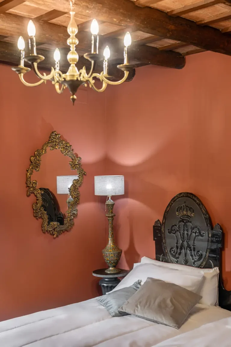 dormitorio clasico pared terracota candelabro dorado cama y espejo barroco