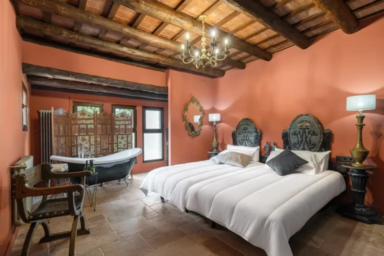dormitorio con dos camas individuales banera exenta y paredes terracota