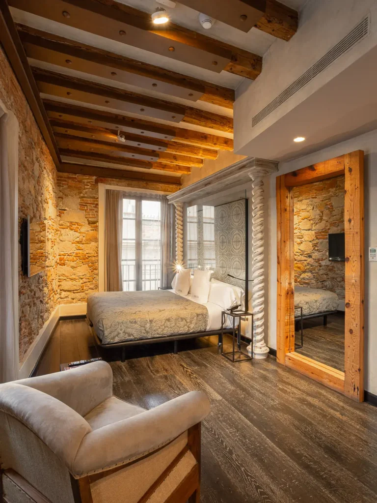 dormitorio con vigas de madera cama doble y sillon tapizado
