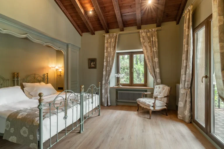 dormitorio luminoso con cama de hierro sillon y ventanales