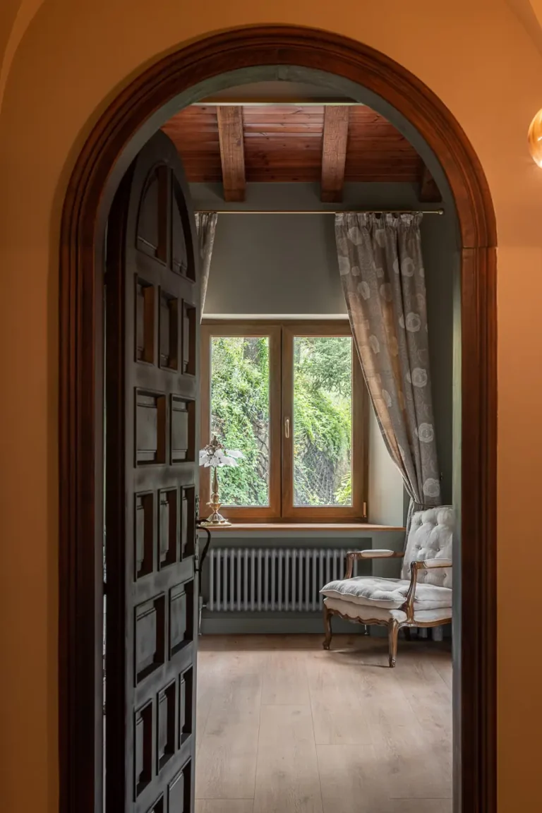entrada arqueada a habitacion con sillon y ventana al jardin