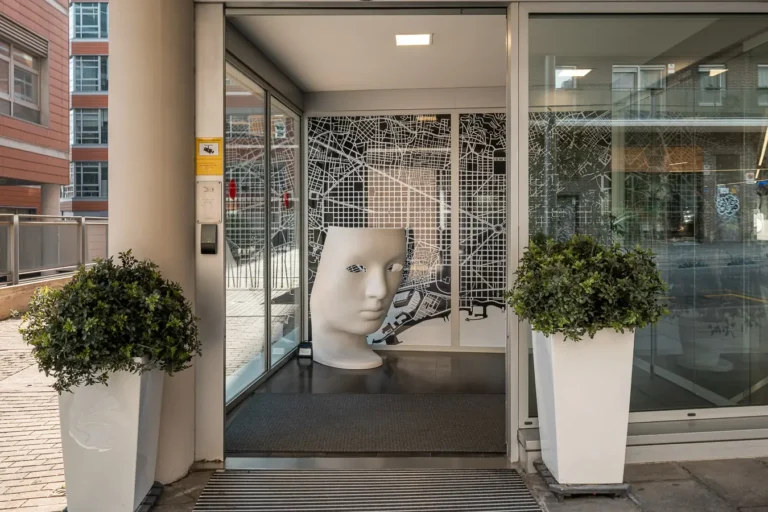 entrada de hotel con escultura y jardineras