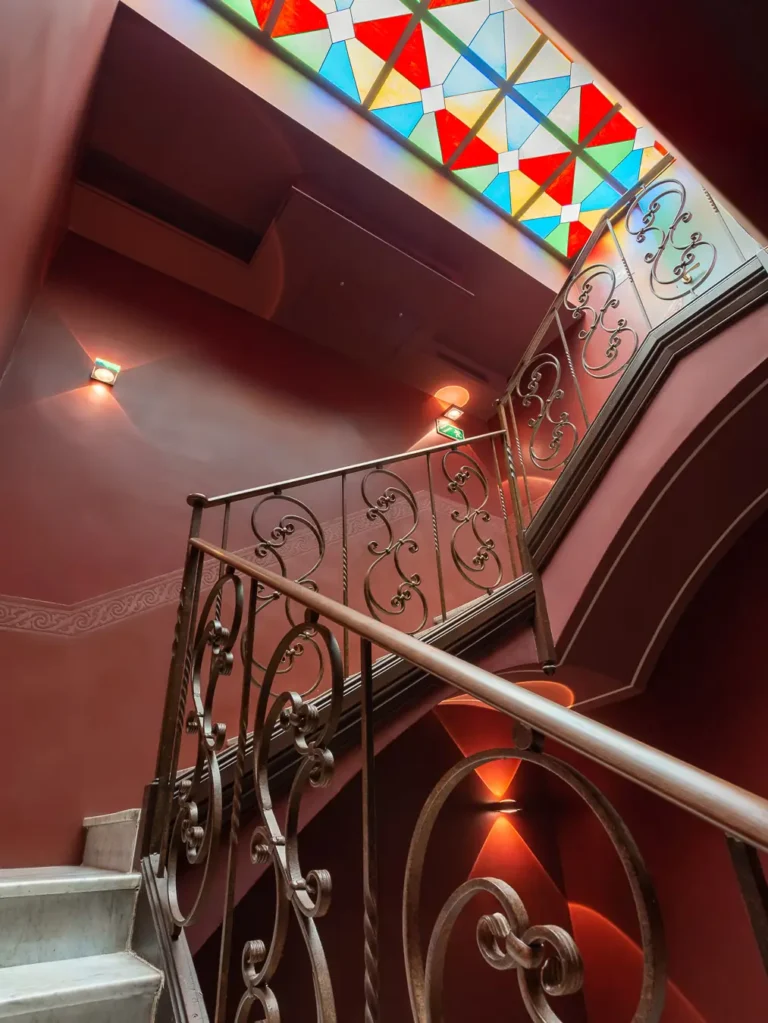 escalera con barandilla de hierro forjado y vidriera de colores