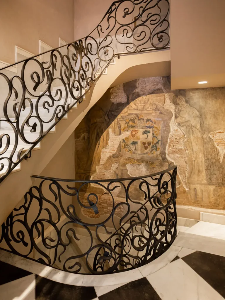 escalera curva con barandilla de hierro y mural historico