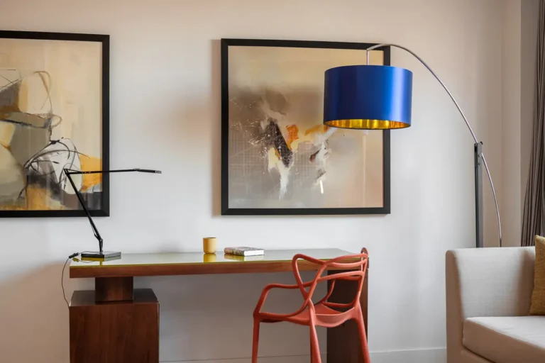 escritorio de hotel con silla roja lampara azul y arte