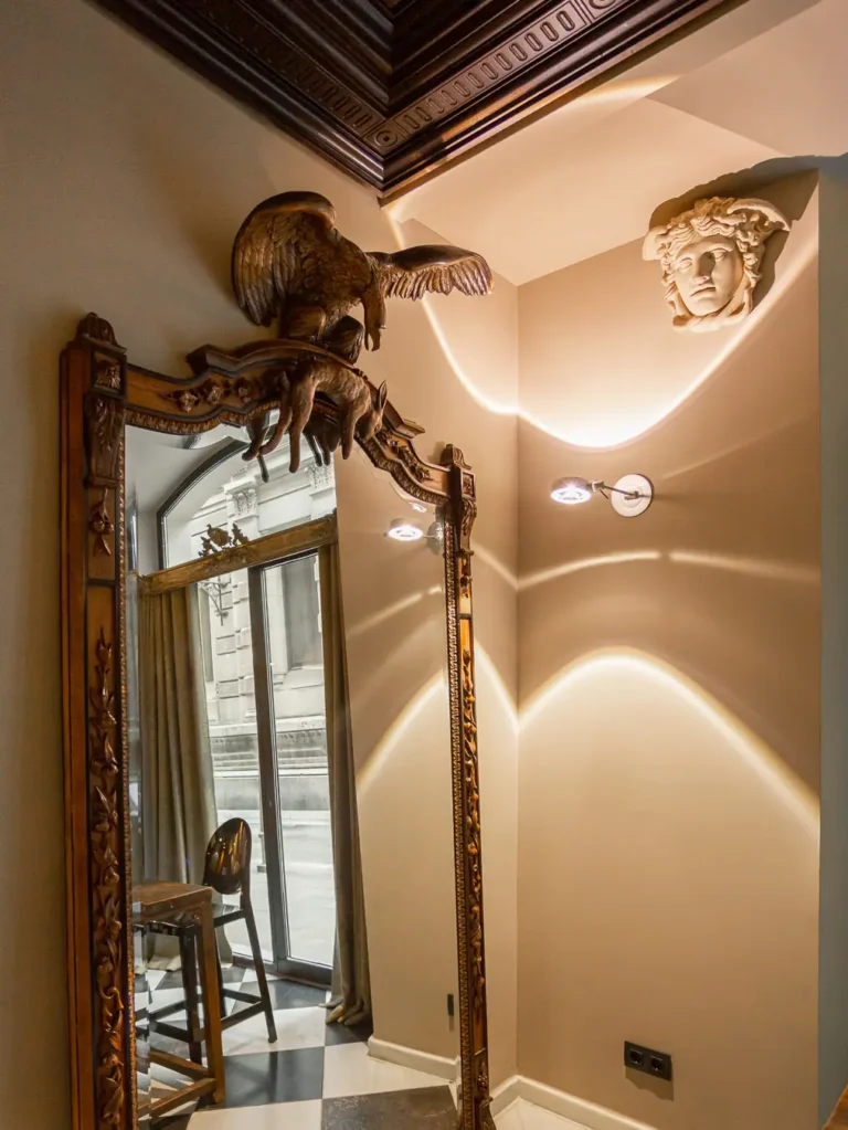 espejo antiguo con escultura de ave y apliques en vestibulo