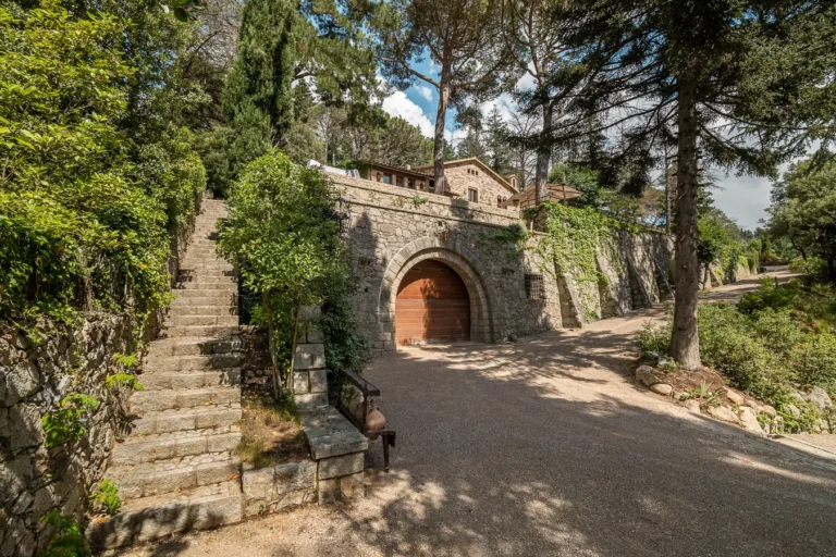 exterior de casa de piedra con escalera jardin y acceso a garaje