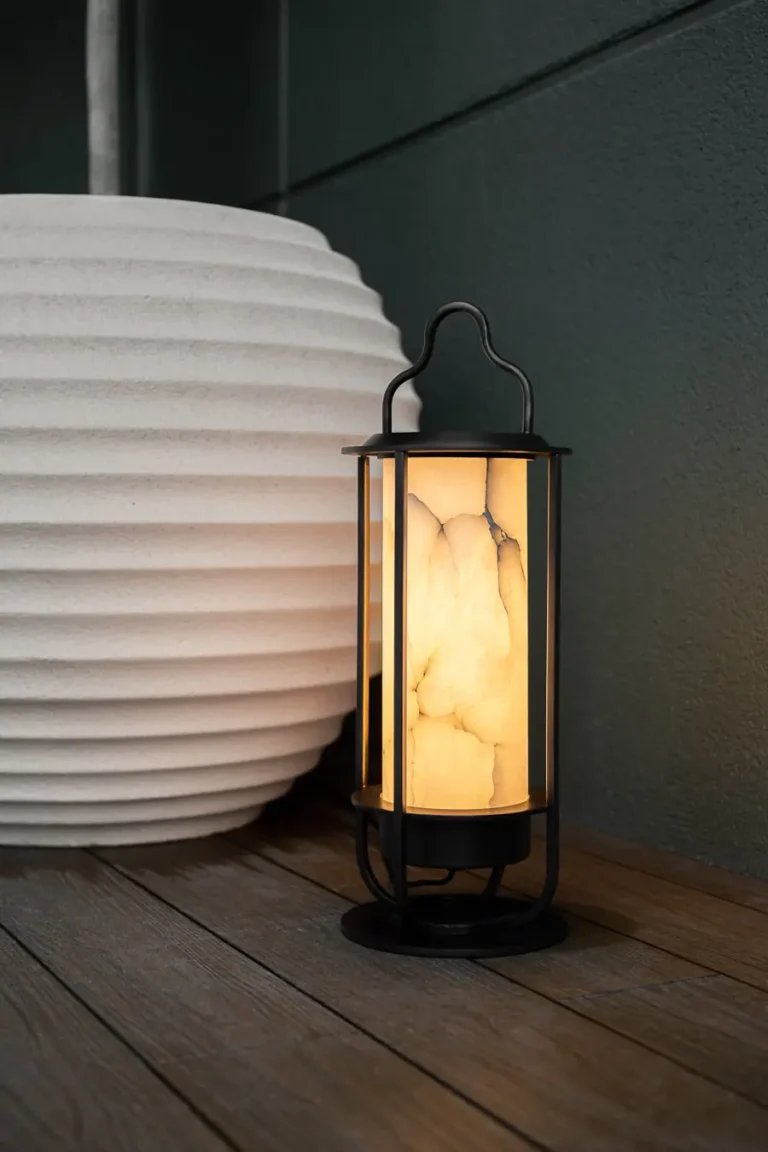 farol decorativo iluminado junto a macetero blanco