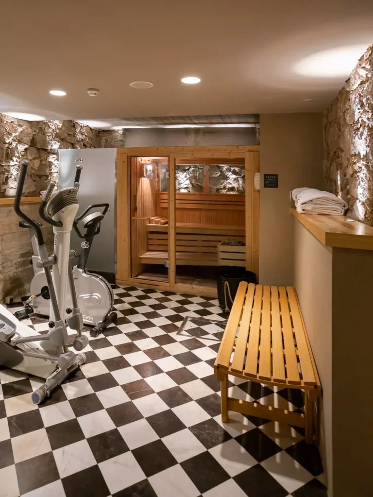 gimnasio con bicicleta eliptica sauna de madera y suelo ajedrezado