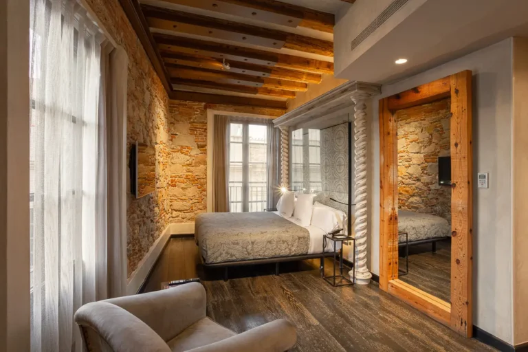 habitacion amplia con cama doble paredes de piedra y espejo