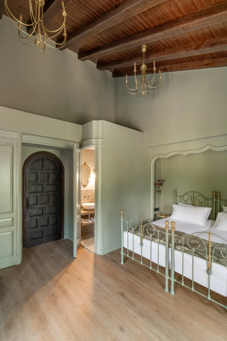 habitacion clasica con cama de hierro y vigas de madera