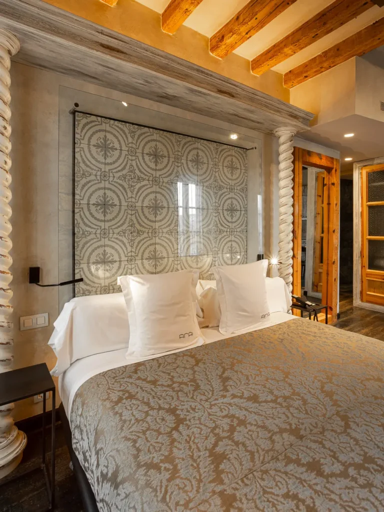 habitacion con cama doble cabecero de azulejos decorativos y vigas de madera