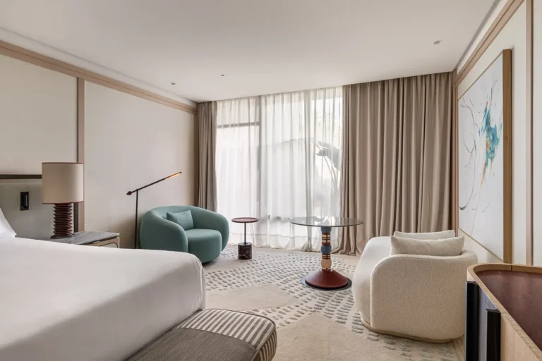habitacion de hotel con cama sillones y ventanales