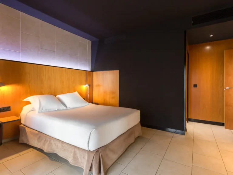 habitacion hotel cama doble paneles madera y lamparas