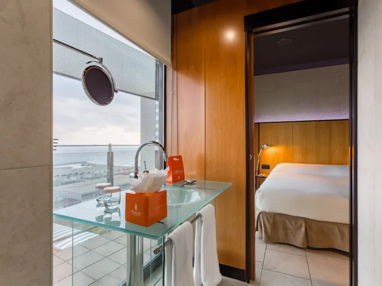 lavabo abierto de suite hotel con vistas al mar y dormitorio