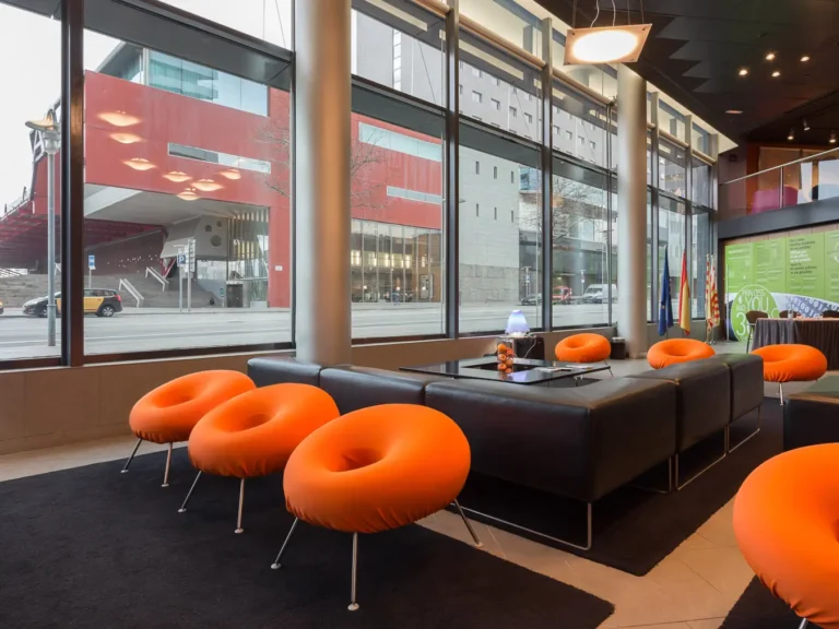 lobby hotel con sillones naranjas y grandes ventanales