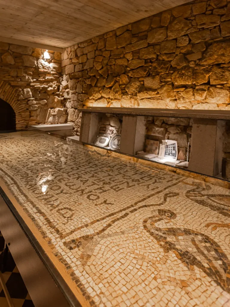 mosaico antiguo expuesto en sala de muros de piedra