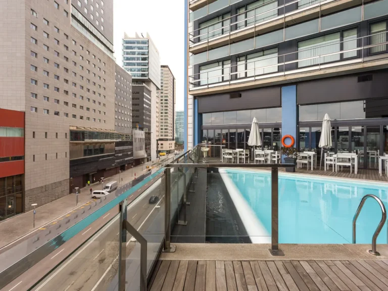 piscina exterior hotel con terraza y vistas urbanas