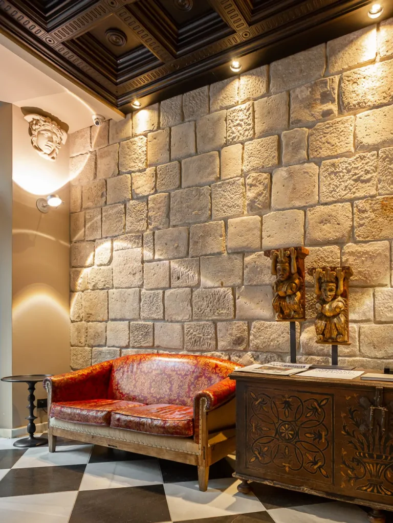 rincon de salon con sofa rojo pared de piedra y arcon antiguo