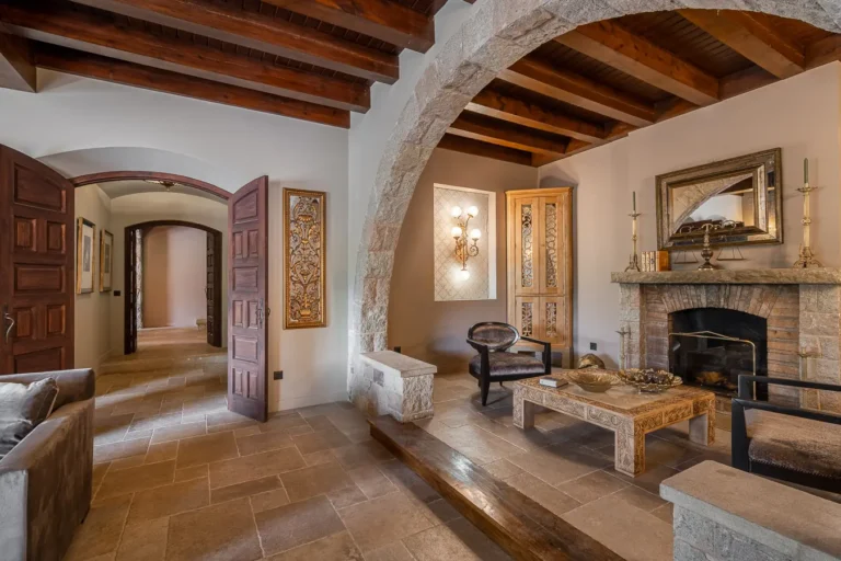 sala de estar con arco de piedra chimenea y techo de madera