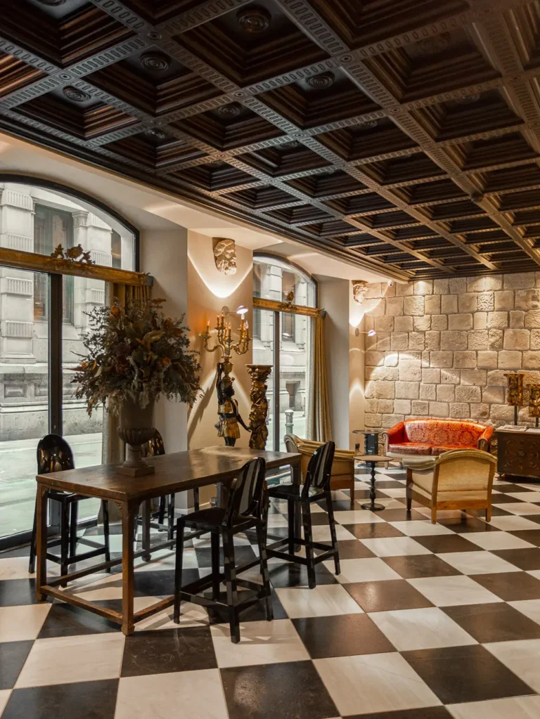 salon con mesas de madera ventanales y techo artesonado oscuro