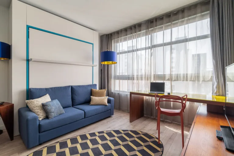 salon de hotel con sofa azul escritorio y ventanales