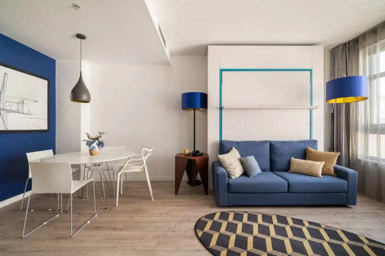 salon de hotel con sofa azul mesa y cama plegable