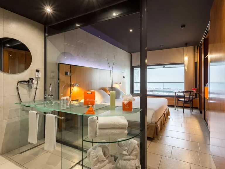 suite hotel con lavabo abierto cama y vistas ciudad