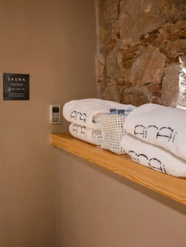 toallas blancas y botellas de agua en estante junto a la sauna