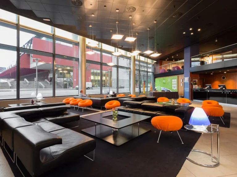 vestibulo hotel amplio con sofas negros y butacas naranjas